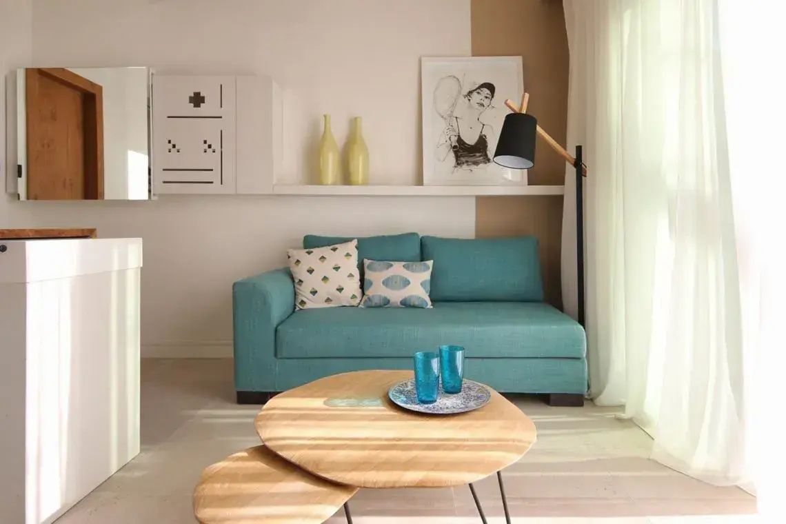 Ein türkisfarbenes Sofa mit modernem Holztisch und Stehlampe im hellen Wohnbereich.