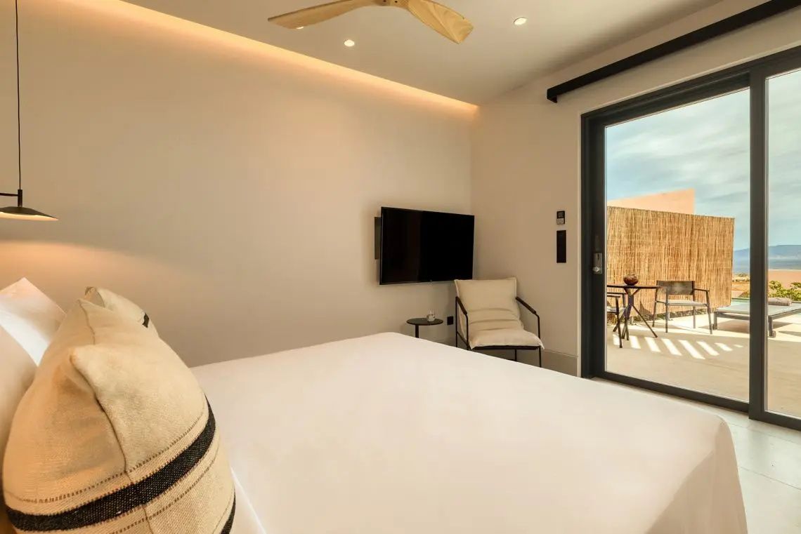 Helles Hotelzimmer mit großem Bett, Fernseher und Zugang zur eigenen Terrasse.