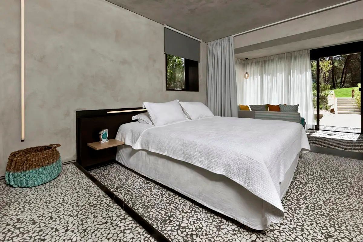Doppelbett mit weißer Bettwäsche und dunklem Kopfteil in einem modern gestalteten Hotelzimmer.