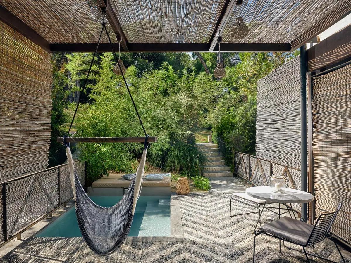 Überdachte Terrasse mit Hängesessel, kleinem Pool und Zickzack-Muster auf dem Boden.