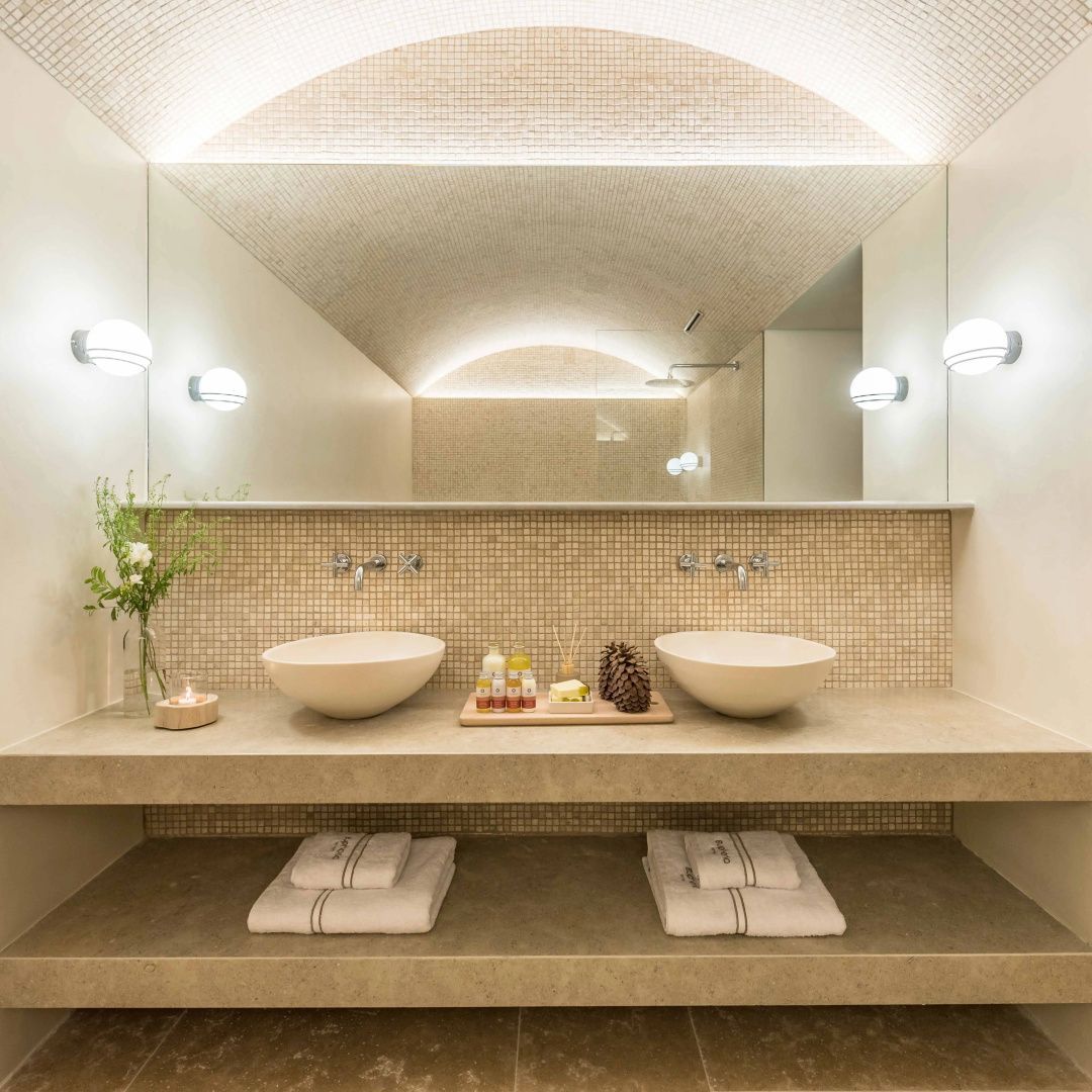 Badezimmer mit zwei Aufsatzwaschbecken, großem Spiegel und beleuchteter Gewölbedecke.