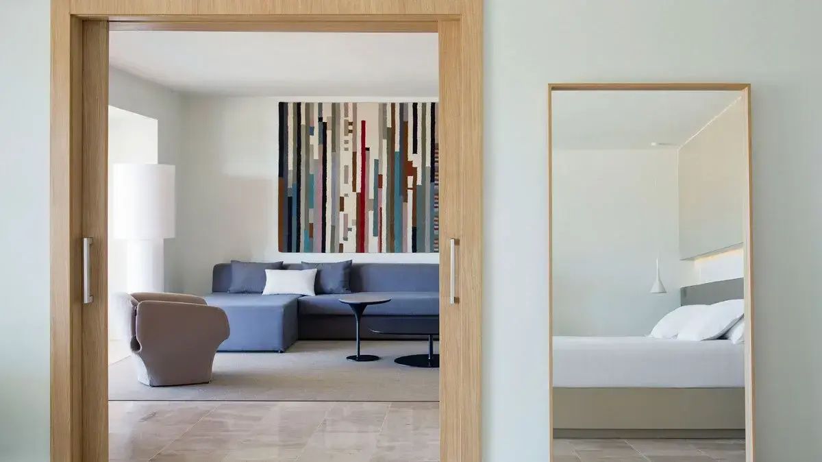 Blick durch einen Türrahmen auf den modernen Wohnbereich mit blauem Ecksofa und buntem Wandbild.