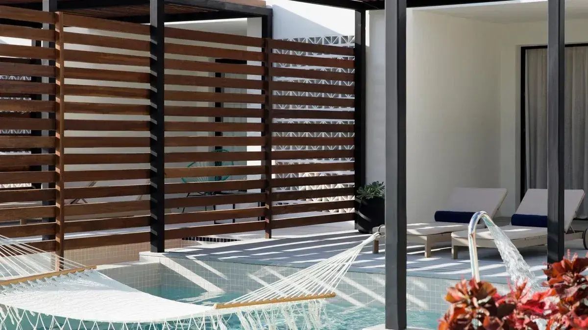 Terrasse mit integriertem Pool, aufgespannter Hängematte und Sichtschutz aus dunklem Holz.