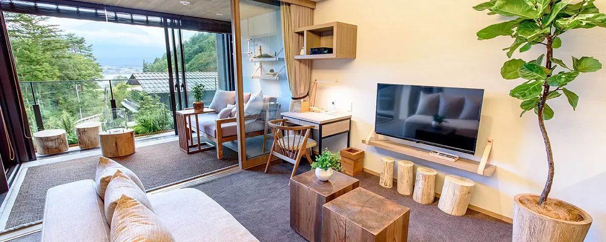 Hotelzimmer mit Holzschreibtisch, Fernseher und Zugang zum verglasten Balkonbereich.