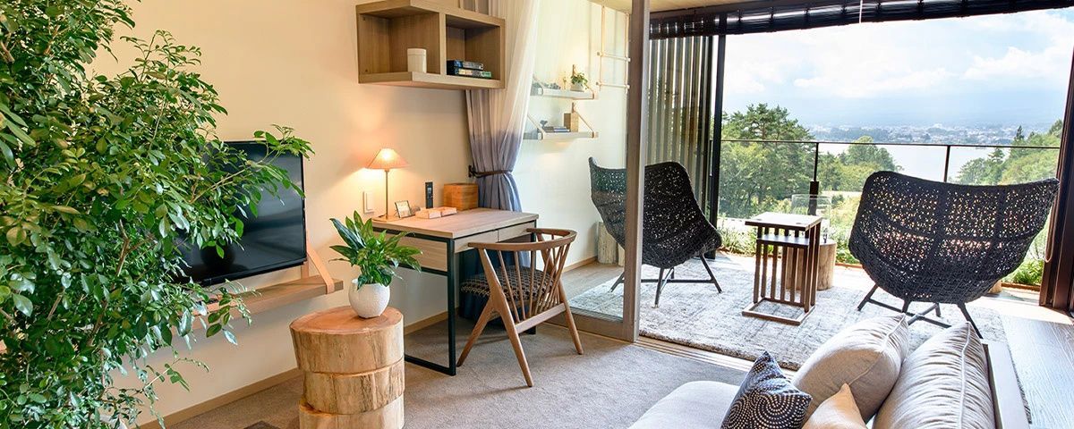 Schreibtisch mit Stuhl, Tischlampe und Zimmerpflanzen in einem modern eingerichteten Hotelzimmer.