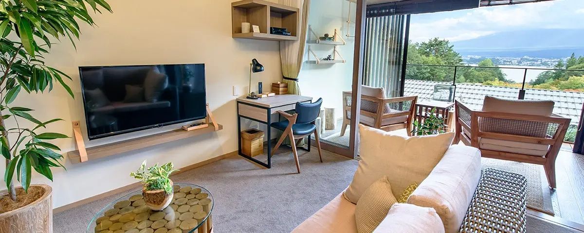 Schreibtisch mit Stuhl und Tischlampe sowie Fernseher im modern eingerichteten Zimmer.