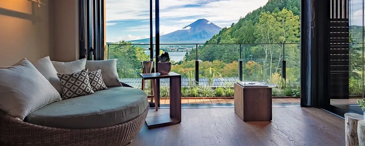 Blick von der Holzterrasse auf den Berg Fuji, den See Kawaguchi und umliegende Wälder.