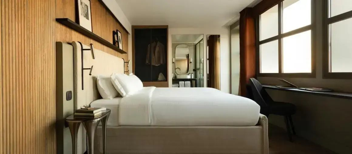 Doppelbett mit weißer Bettwäsche in einem modern eingerichteten Hotelzimmer mit Holzpaneelen.