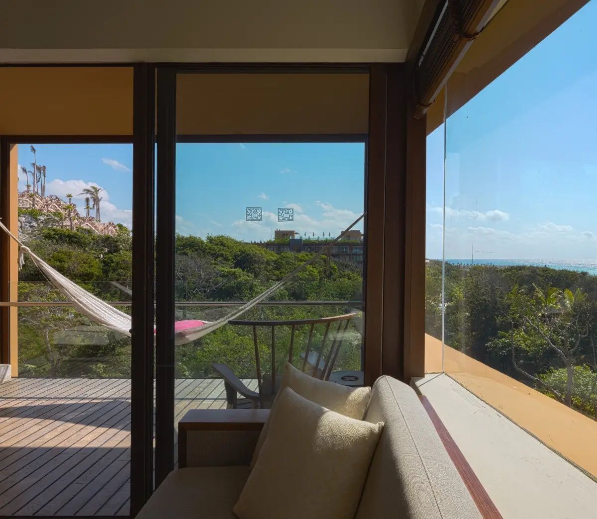 Blick aus dem Hotelzimmer auf einen Balkon mit Hängematte und tropische Natur.