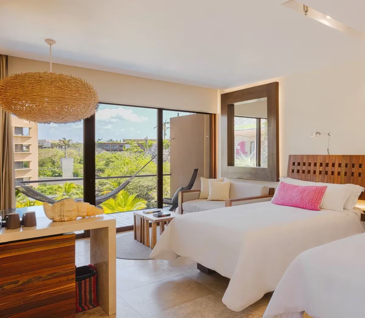 Geräumiges Hotelzimmer mit zwei Betten, Holzmöbeln und Balkon mit Aussicht.