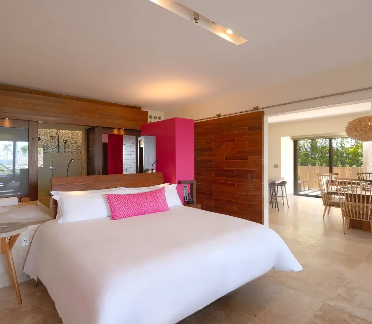 Großes Doppelbett mit weißer Bettwäsche und pinkfarbenem Kissen im Hotelzimmer.