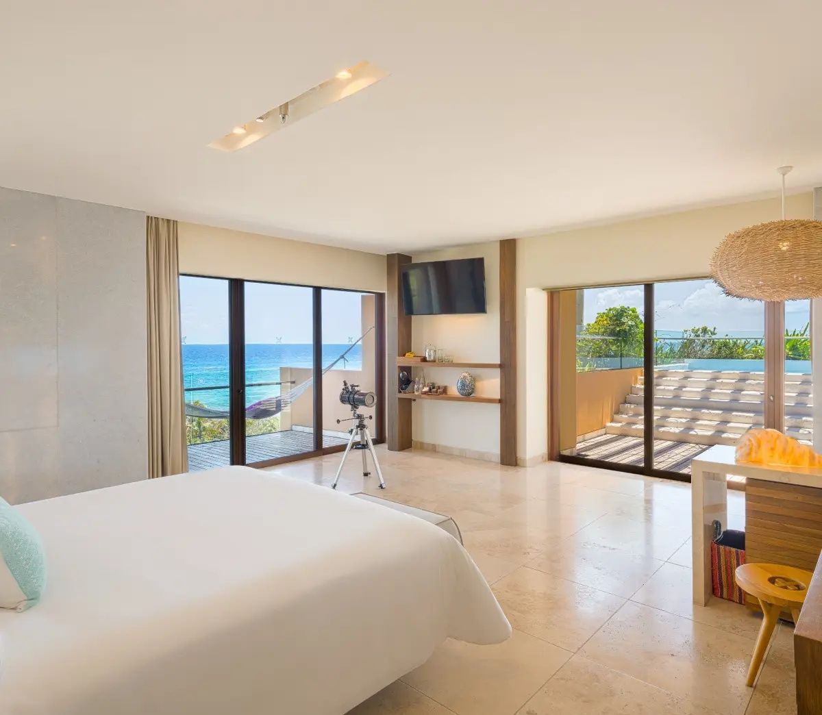 Geräumiges Schlafzimmer mit großem Bett, Teleskop und Zugang zum Balkon mit Meerblick.