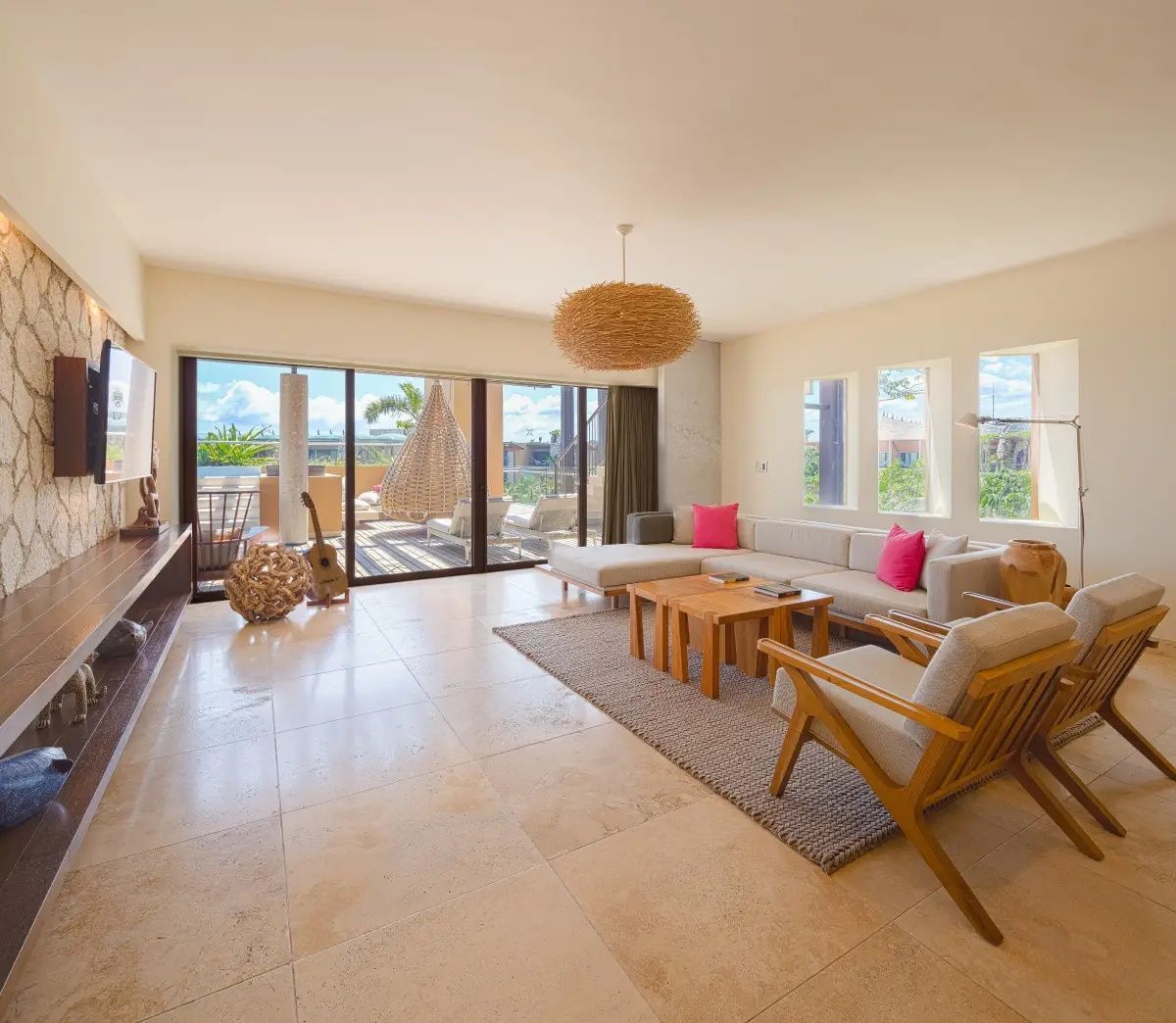 Wohnbereich einer Suite mit hellem Ecksofa, Holztisch und großer Fensterfront zur Terrasse.