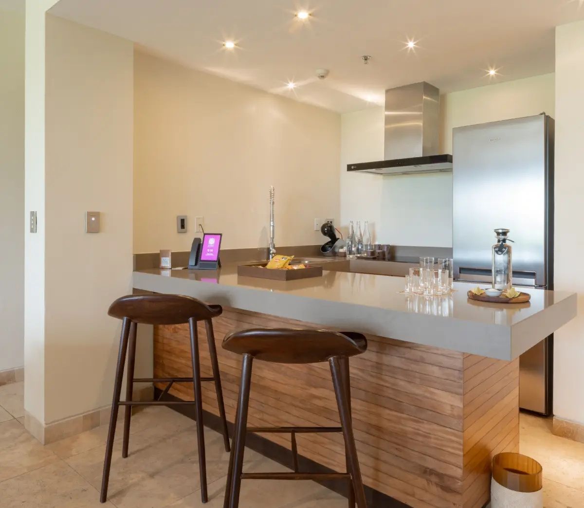 Küchenzeile in der Suite mit Tresen aus Holz, zwei Barhockern und Edelstahlgeräten.
