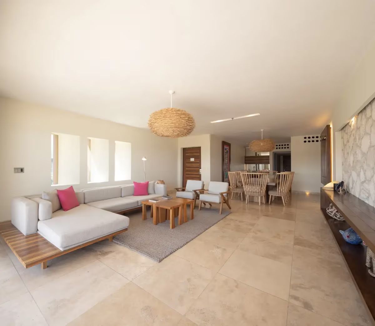 Offener Wohnbereich und Essbereich einer Suite mit hellem Sofa und Rattanlampe.