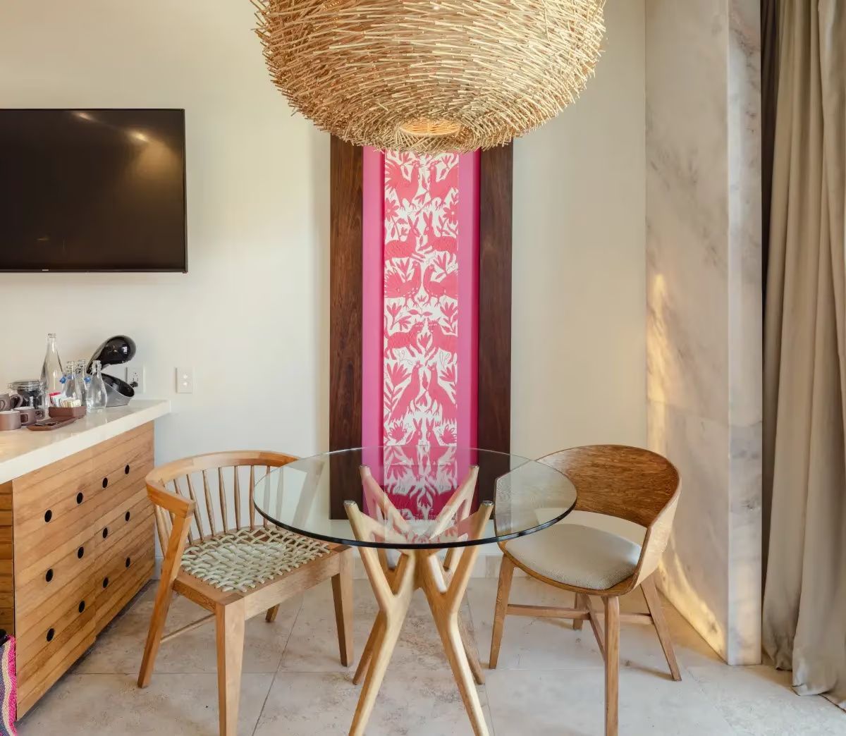 Kleiner Essbereich im Zimmer mit Glastisch, zwei Holzstühlen und großer Lampe.