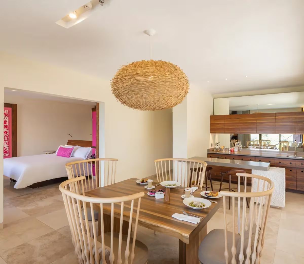 Offener Wohnbereich und Essbereich einer Suite mit Holztisch und Blick ins Schlafzimmer.