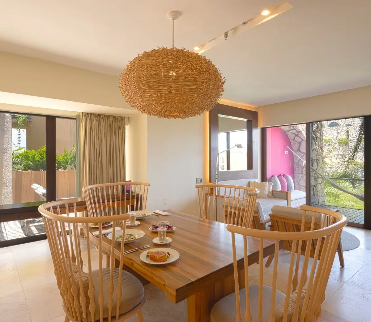 Heller Essbereich der Suite mit großem Holztisch und Blick Richtung Terrasse.