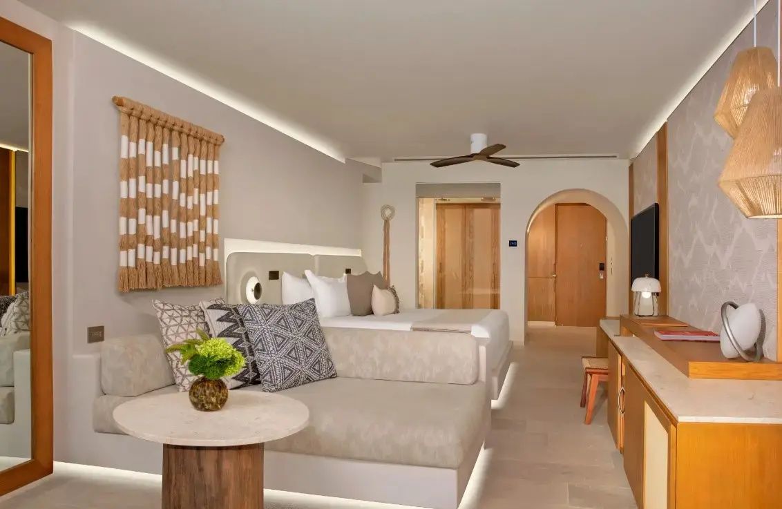 Geräumiges Hotelzimmer mit Couch im Vordergrund und Bett im Hintergrund.