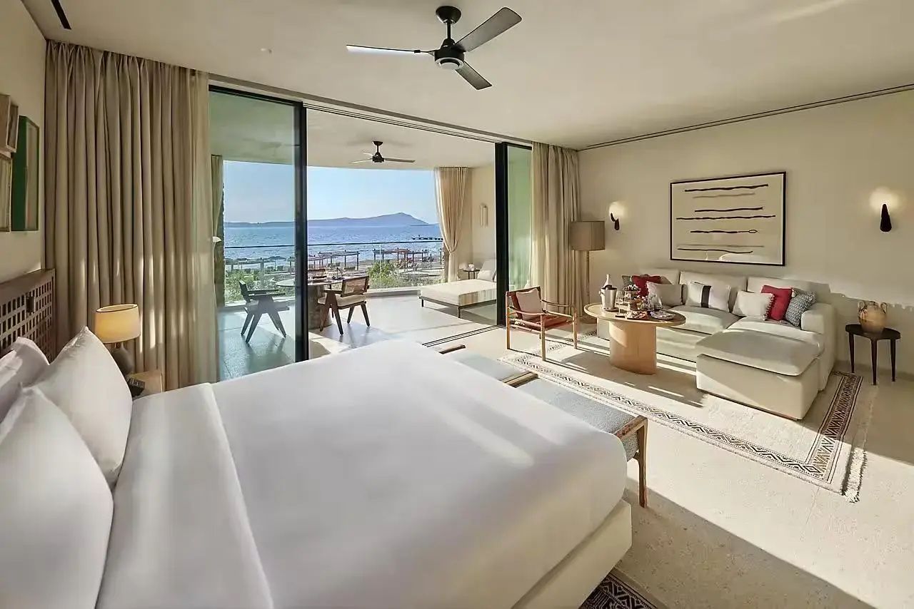 Schlafzimmer mit geöffneter Schiebetür zur Terrasse und Blick auf das Meer sowie die Küste.