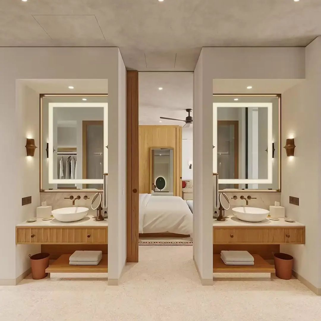 Doppelwaschtisch im Badezimmer mit zwei beleuchteten Spiegeln und Blick auf das angrenzende Schlafzimmer.