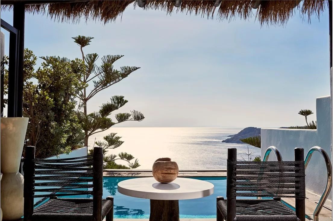 Terrasse mit Tisch, Stühlen und einem kleinen Pool mit weitem Blick auf das Meer.