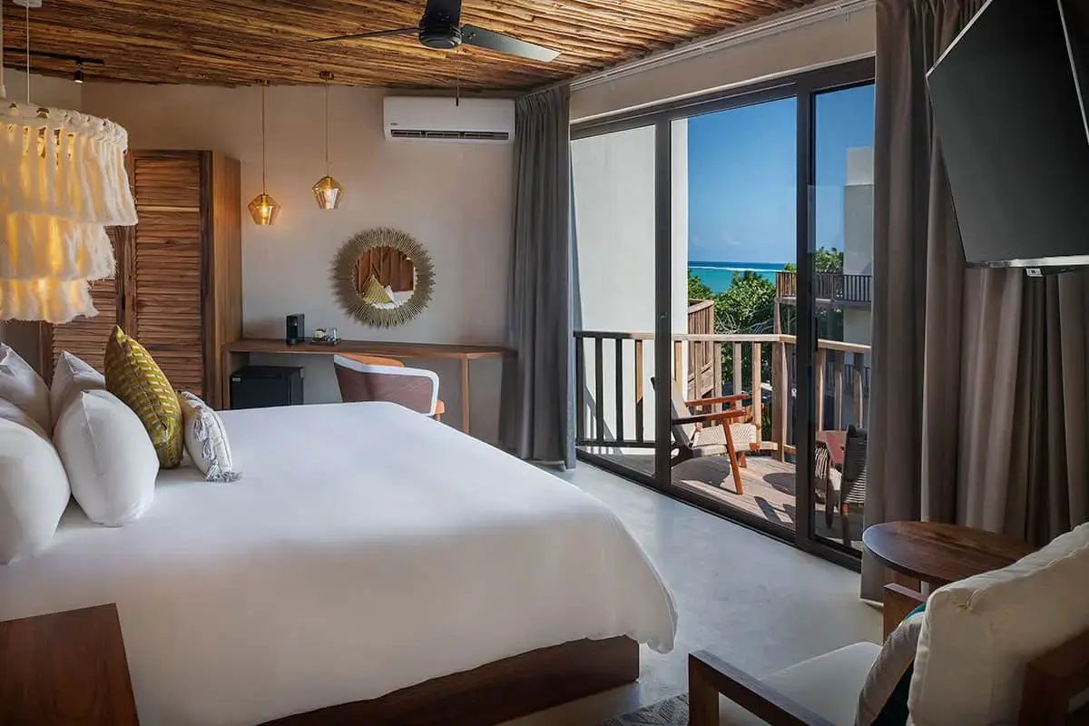 Schlafzimmer mit großem Bett, Schreibtisch und Balkontür mit Blick auf die Küste.