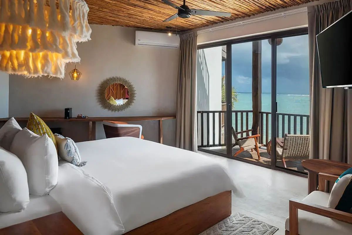 Schlafbereich im Hotelzimmer mit runder Wanddekoration, Bett und Balkon mit Meeresblick.