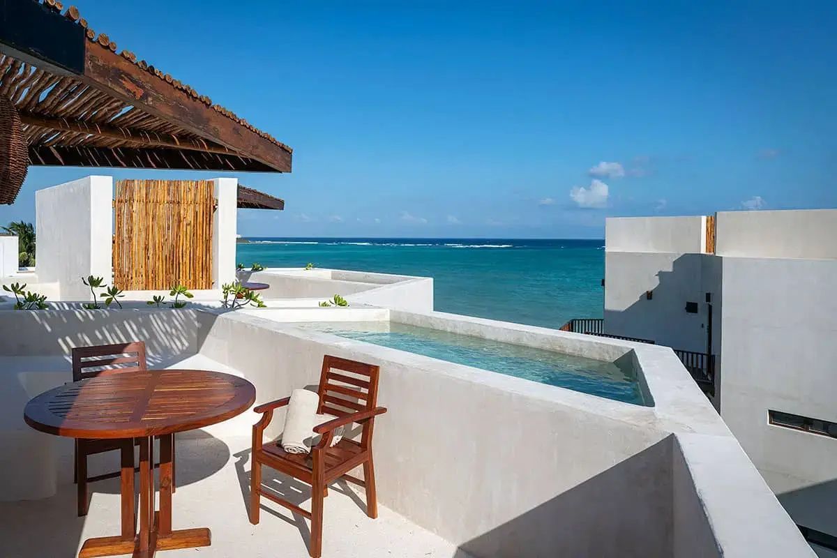 Dachterrasse mit kleinem Pool, Holztisch und Ausblick auf das türkisblaue Meer.