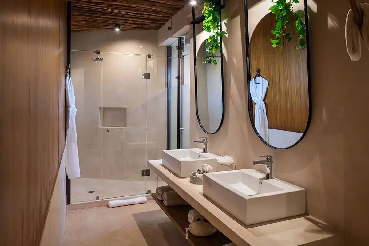 Modernes Badezimmer mit zwei Waschbecken, ovalen Spiegeln und bodengleicher Dusche.