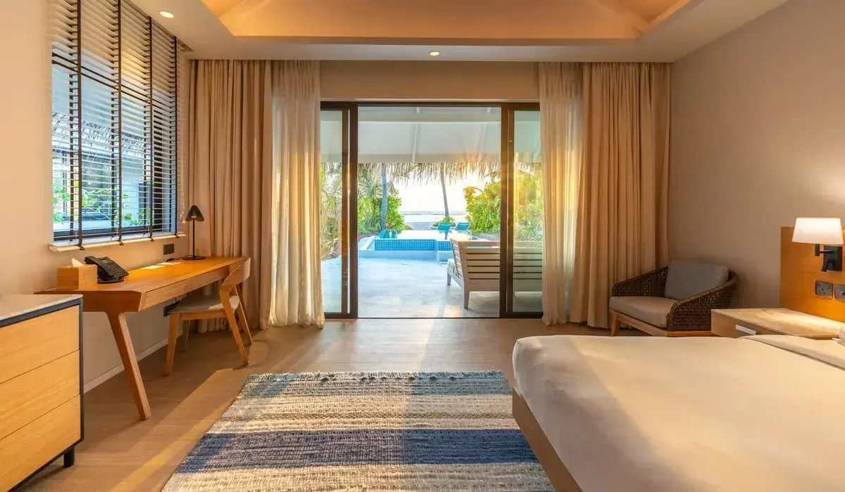 Blick aus dem Schlafzimmer durch geöffnete Glastüren auf eine Terrasse mit privatem Pool.