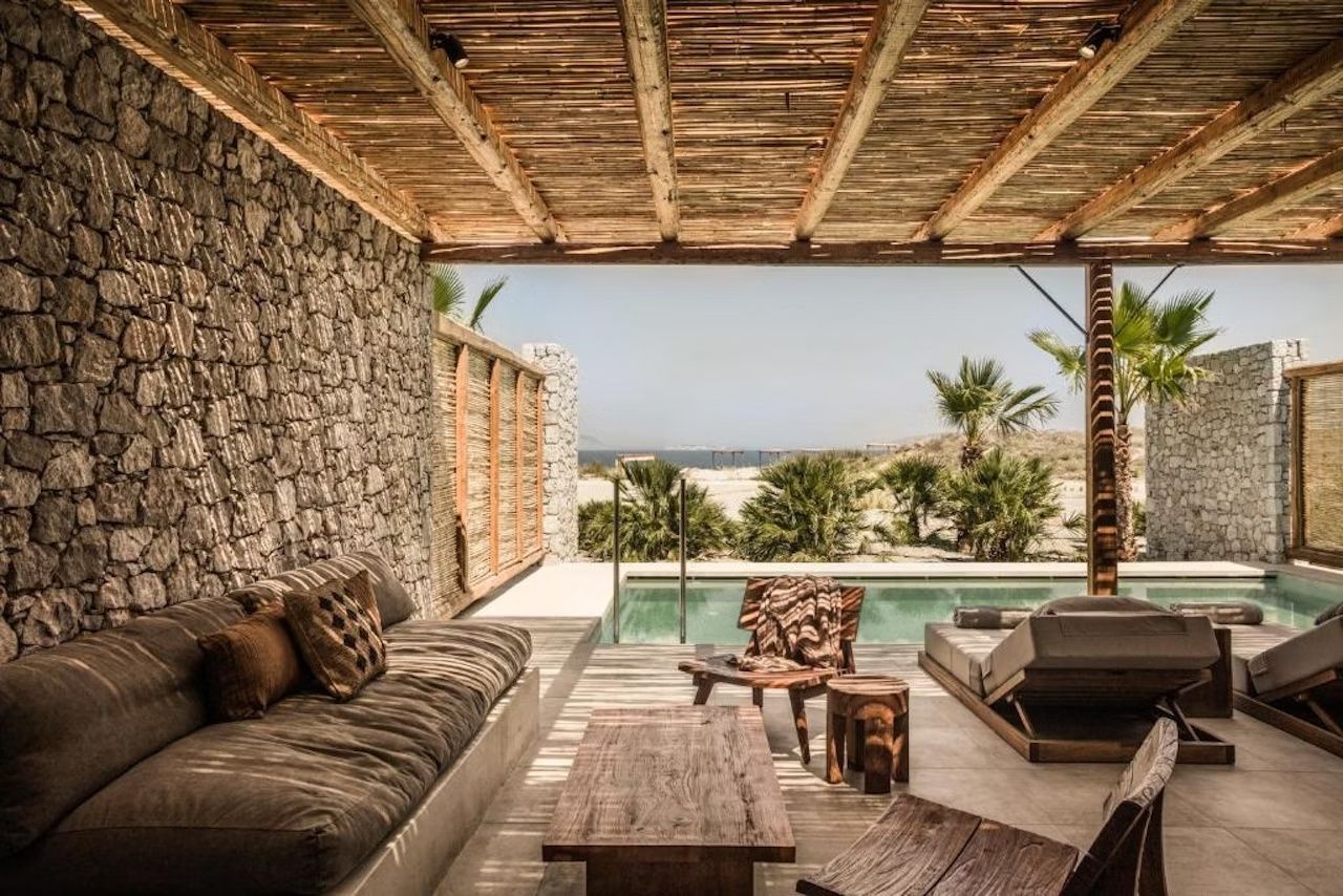 Überdachte Terrasse mit Steinwand und Holzmöbeln direkt am eigenen Swimmingpool.