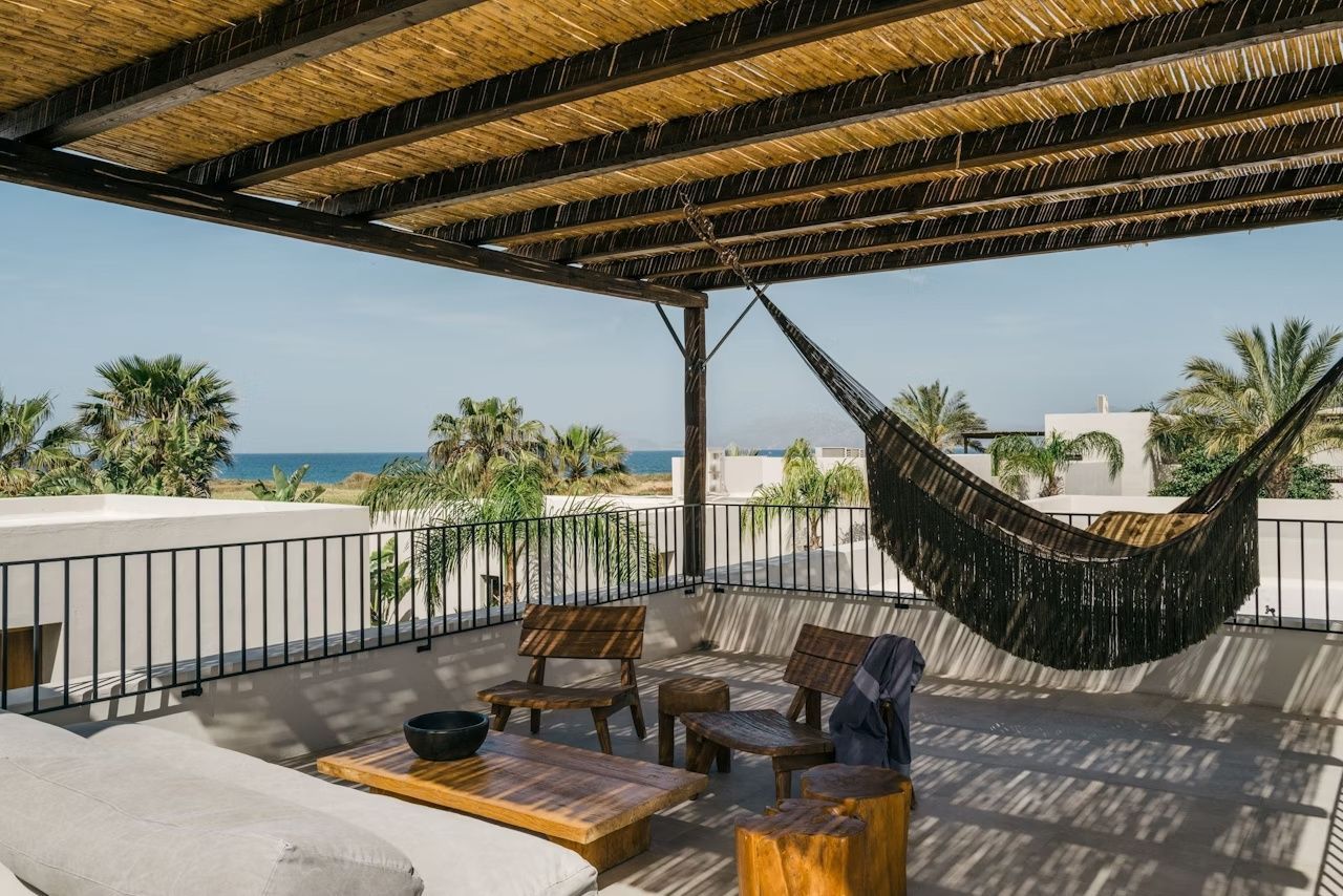 Dachterrasse mit Holzmöbeln, Hängematte und Überdachung mit Blick auf das Meer.