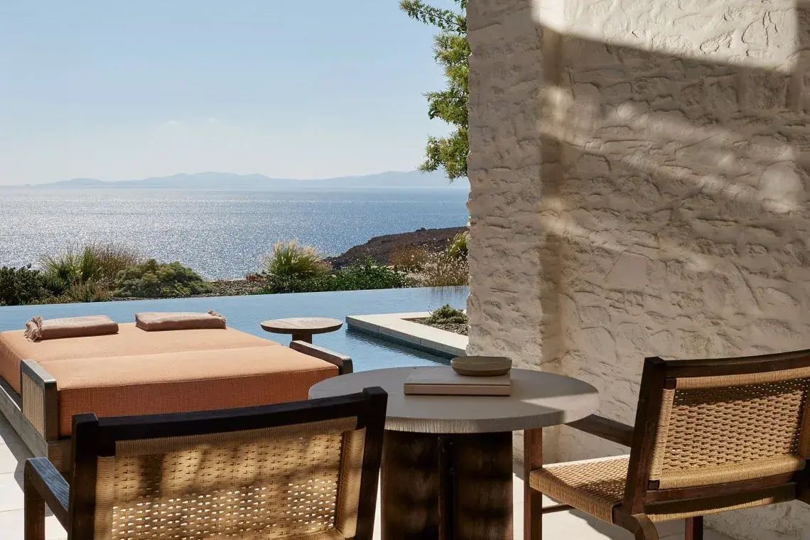 Terrasse mit Sonnenliege, Tisch und einem Infinity Pool vor dem offenen Meer.