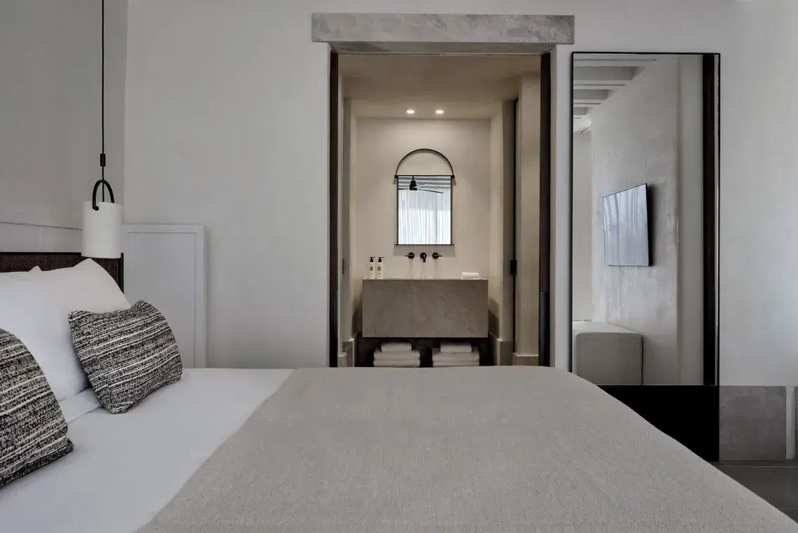 Schlafzimmer im minimalistischen Stil mit Blick auf das angrenzende Badezimmer.