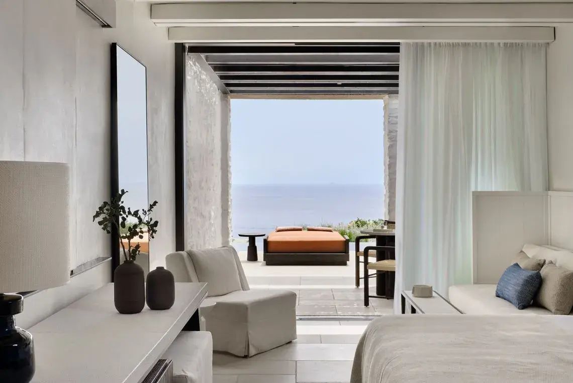 Blick aus dem Zimmer durch eine große Öffnung auf die Terrasse und das weite Meer.