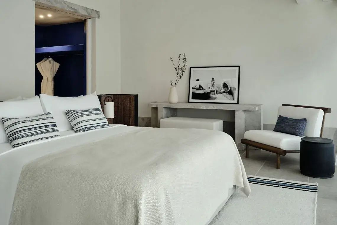 Helles Schlafzimmer im Hotel mit weißem Doppelbett, Konsole und Bild an der Wand.