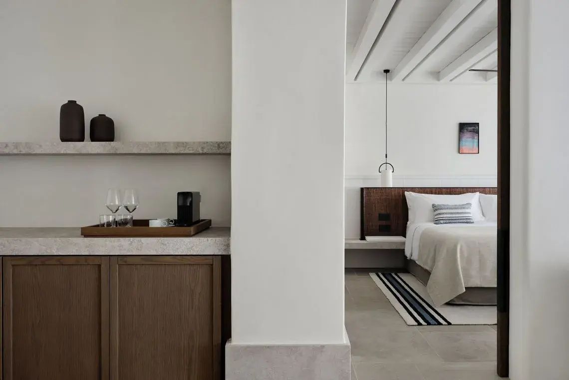 Helles Hotelzimmer mit Doppelbett, Holz-Headboard und einer kleinen Kaffeebar.