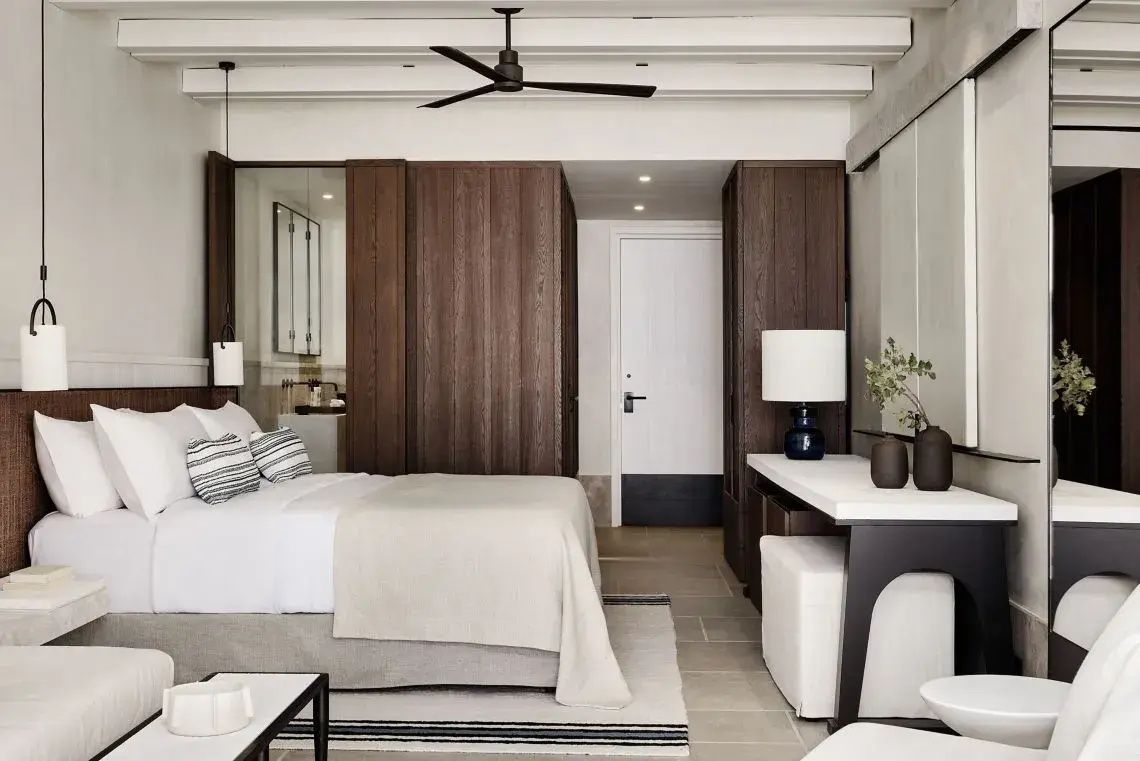 Hotelzimmer mit Doppelbett, Schreibtisch, Deckenventilator und dunklen Schränken.