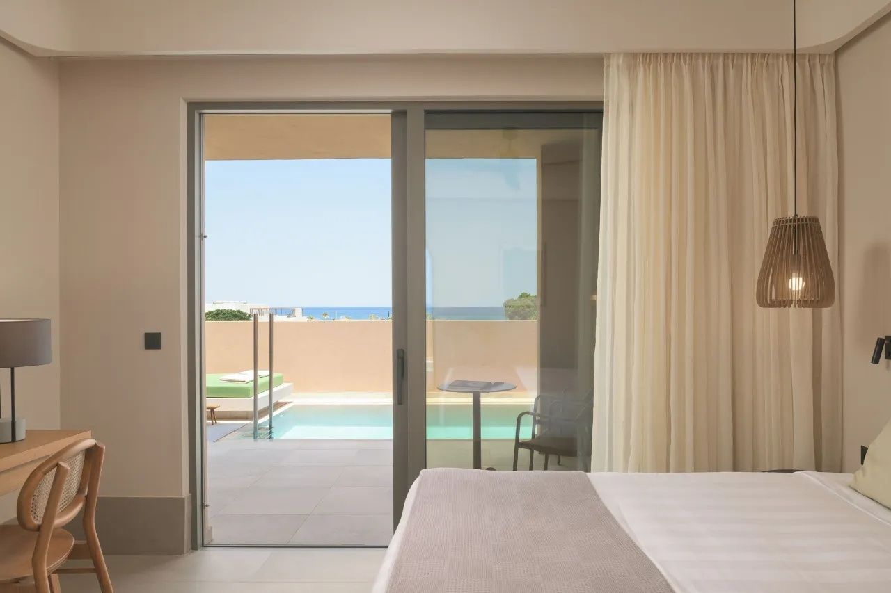 Blick durch die Glasflügeltür auf die Terrasse mit privatem Pool und das Meer.
