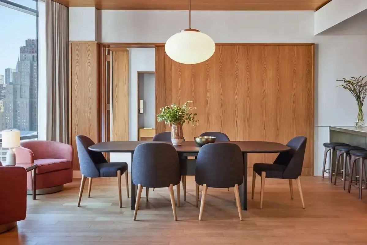 Essbereich in einer Suite mit einem ovalen Esstisch, dunkelgrauen Stühlen und Holzvertäfelung.