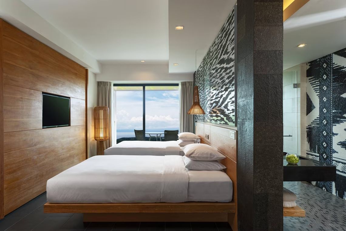 Zwei Betten in einem Zimmer mit großen Fenstern und Blick auf das Meer.