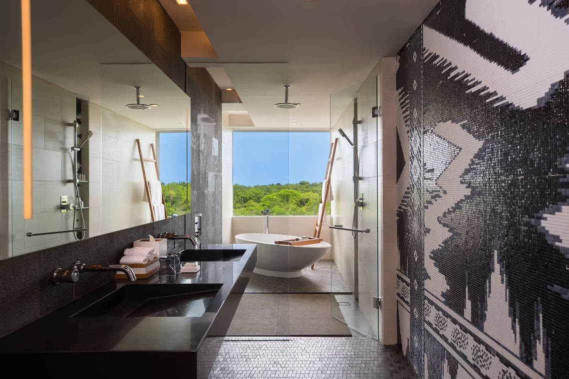 Badezimmer mit Doppelwaschtisch, freistehender Badewanne und Blick auf die grüne Landschaft.
