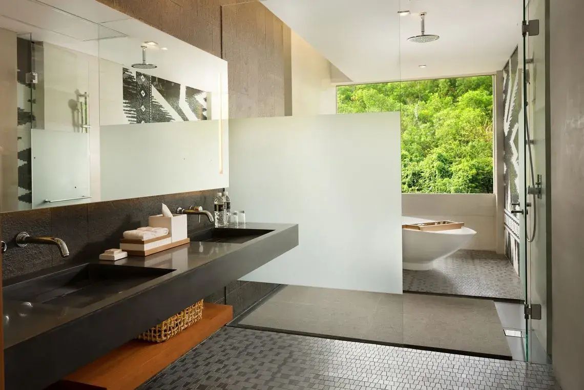 Badezimmer mit dunklem Waschtisch, Dusche und Badewanne am Panoramafenster.