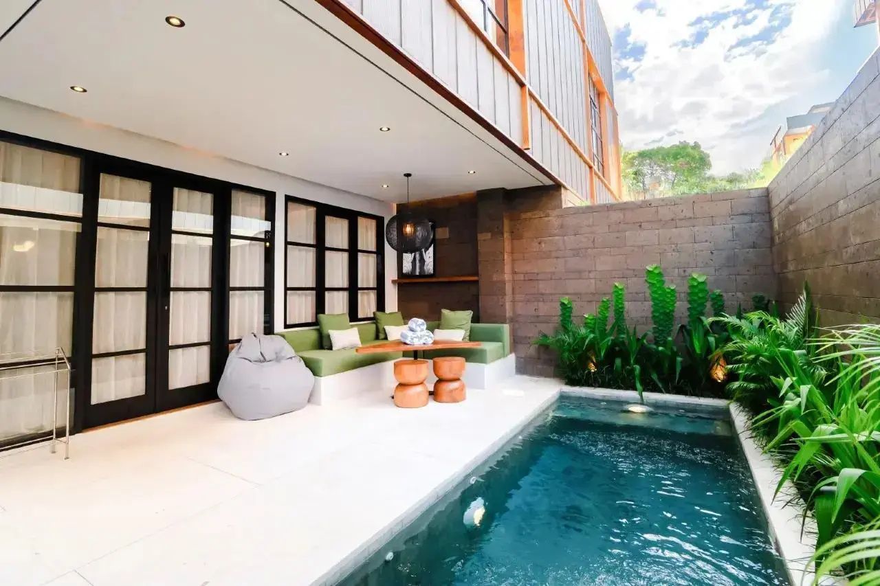 Überdachte Terrasse mit grünem Sitzbereich und einem privaten kleinen Swimmingpool.