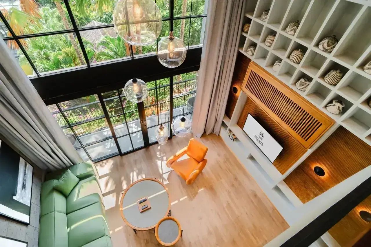 Blick von oben auf den Wohnbereich mit Sofa, Sessel, Tisch und TV-Wand.