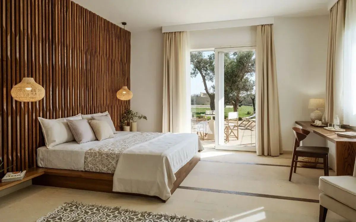 Helles Schlafzimmer mit Holzverkleidung hinter dem Bett und Ausgang zur Terrasse.