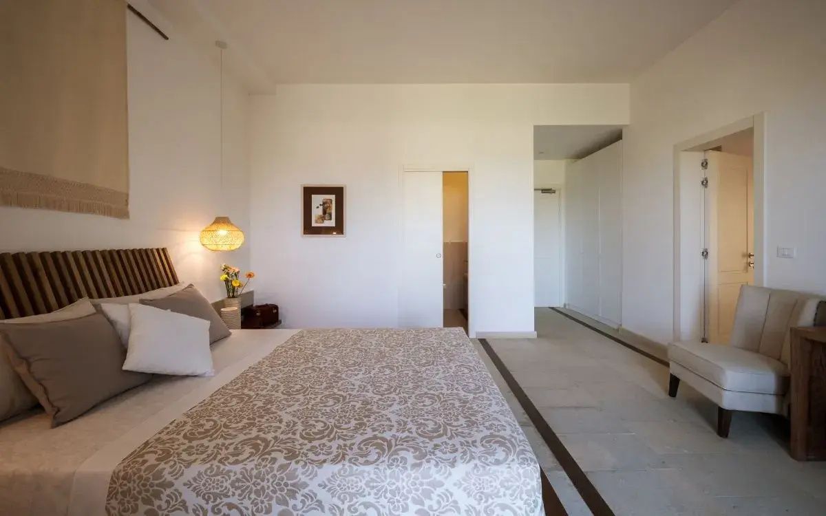 Geräumiges Schlafzimmer mit großem Doppelbett, weißem Einbauschrank und Durchgang zum Bad.