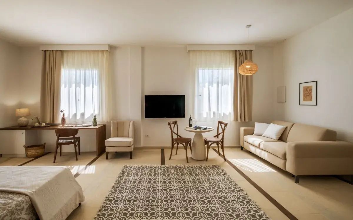 Einrichtung des Wohnbereichs mit Sofa, Fernseher an der Wand und rundem Esstisch.
