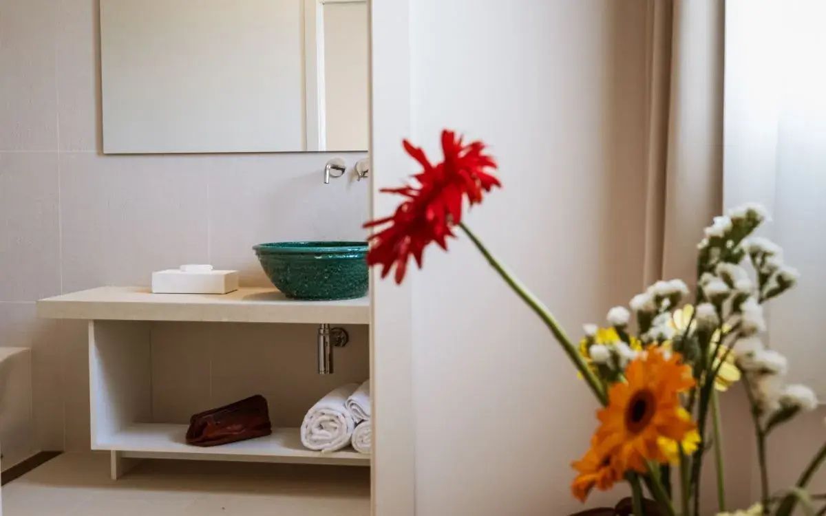 Badezimmer mit einem grünen Aufsatzwaschbecken, hellem Waschtisch und frisch zusammengelegten Handtüchern.
